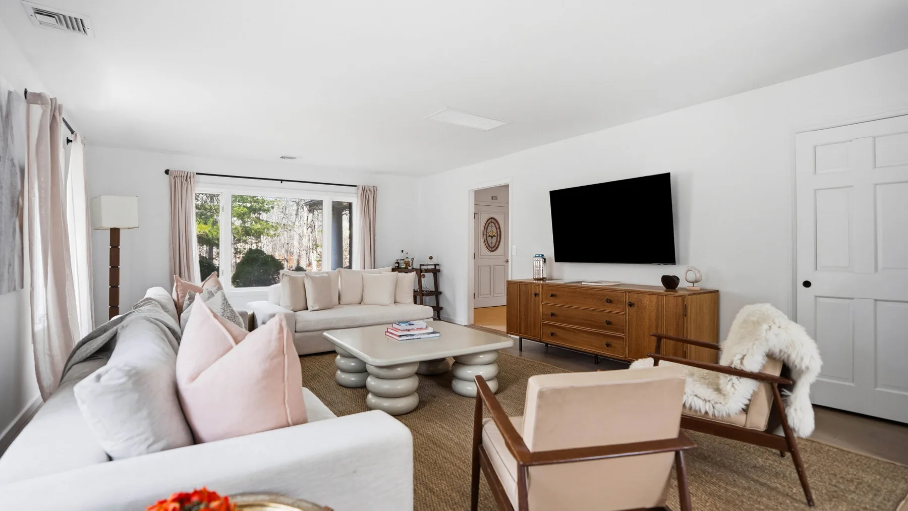 Una sala de estar con asientos acolchados, una mesa de centro y un televisor en la pared.