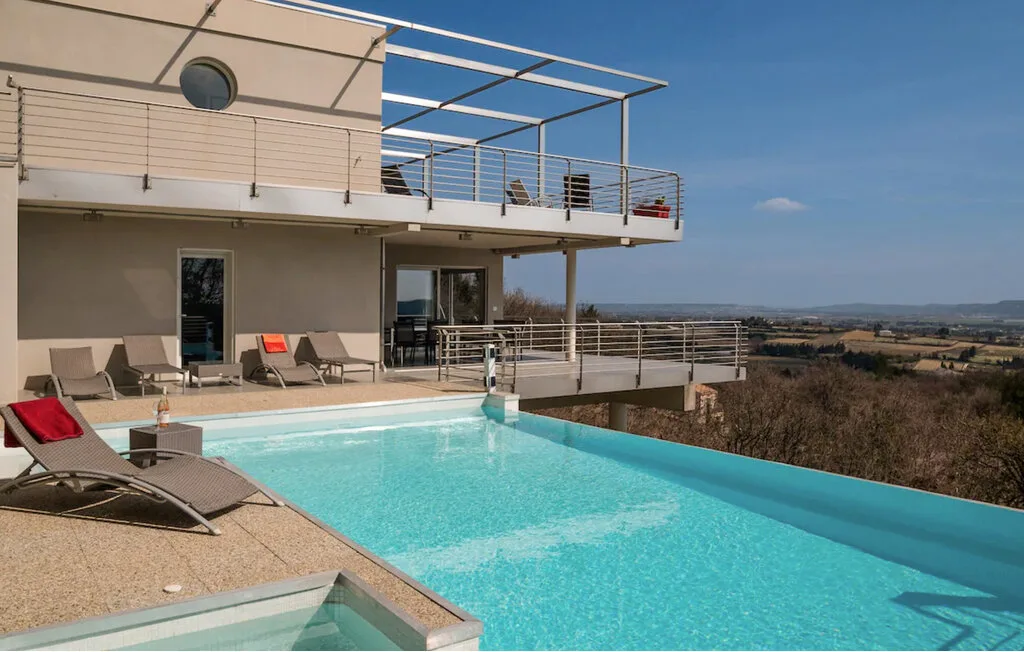Una piscina al aire libre junto a una casa moderna ofrece vistas a un amplio paisaje rural.