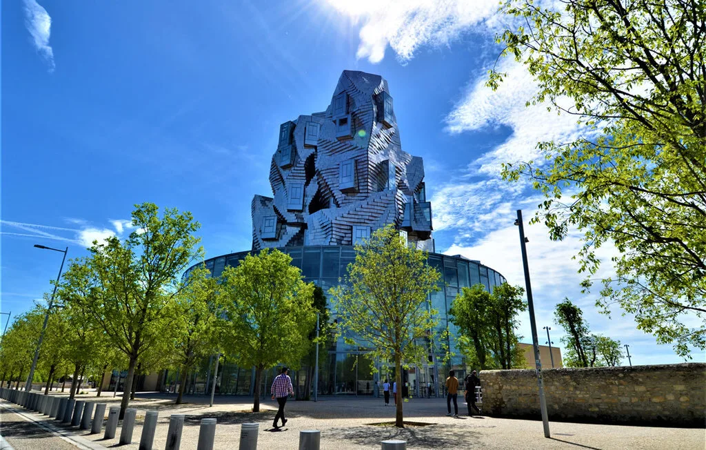 Un edificio moderno distintivo se eleva sobre una planta baja acristalada y árboles frondosos.