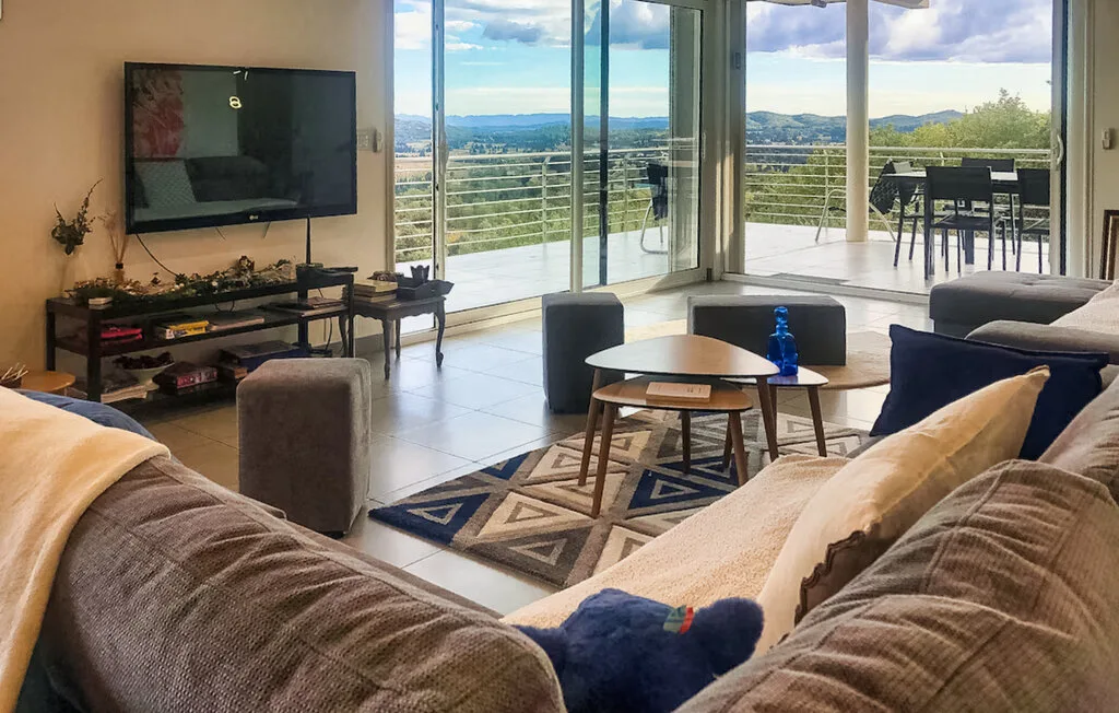 A living room with seating, a television, and large windows overlooking the hills.