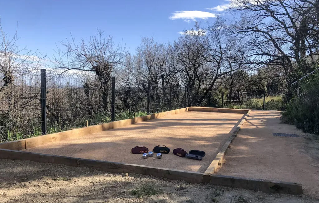Una pista exterior de grava está junto a un área cercada, bordeada de árboles sin hojas.