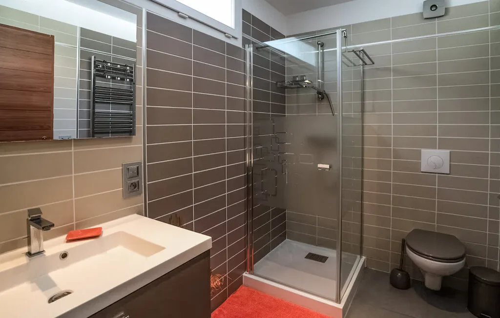 Un baño alicatado con lavabo, ducha de vidrio e inodoro.