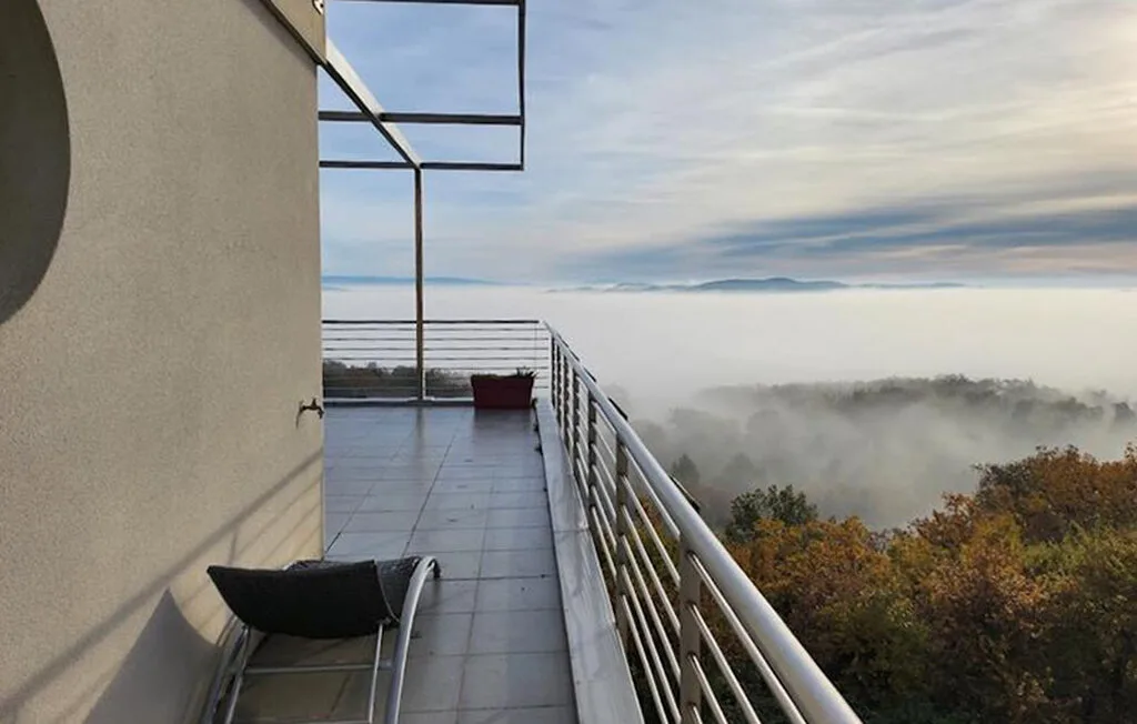 Un balcón da a un paisaje brumoso, con asientos junto a la barandilla.