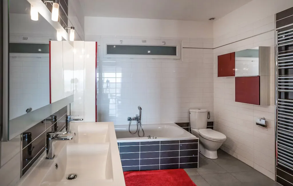 Un baño con azulejos, bañera, lavabo e inodoro.
