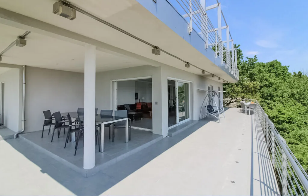 Una amplia terraza exterior con asientos y una puerta de vidrio que da al interior.