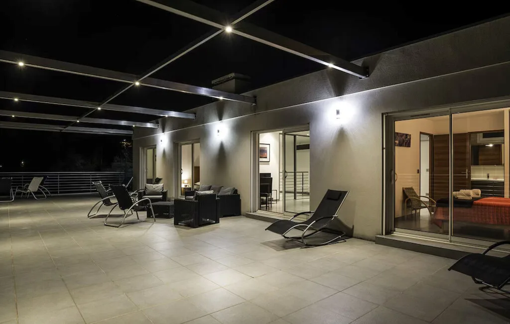 Una terraza exterior con suelo de baldosas, asientos y puertas corredizas de vidrio.