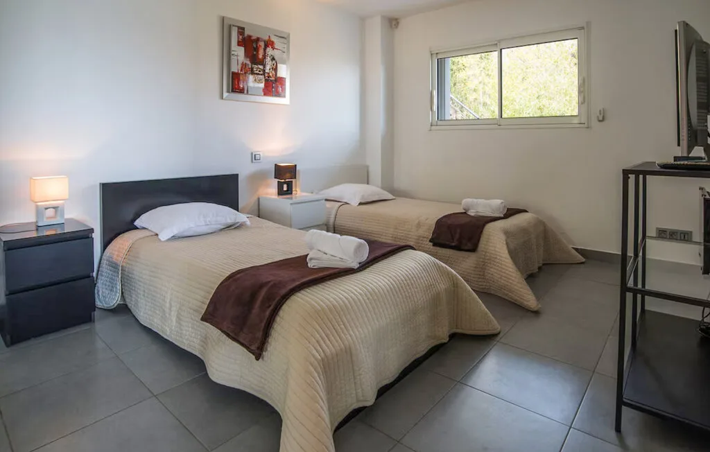 Un dormitorio con dos camas, mesitas de noche y una ventana.
