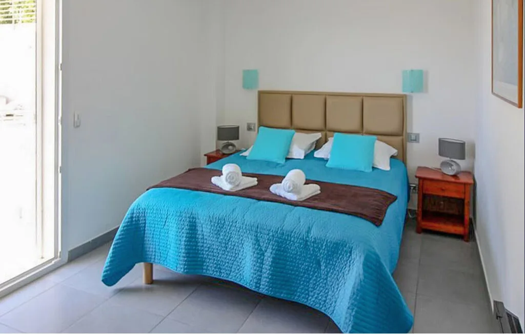 Un dormitorio con una cama doble vestida con ropa de cama turquesa y almohadas a juego.