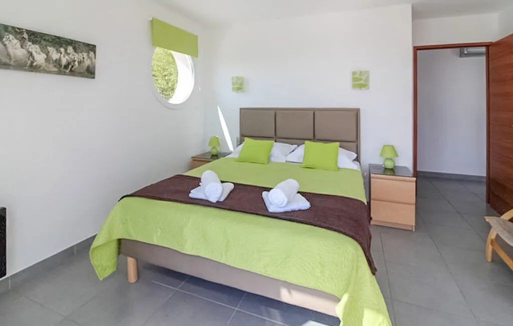Un dormitorio con una cama doble vestida con ropa de cama verde y marrón.