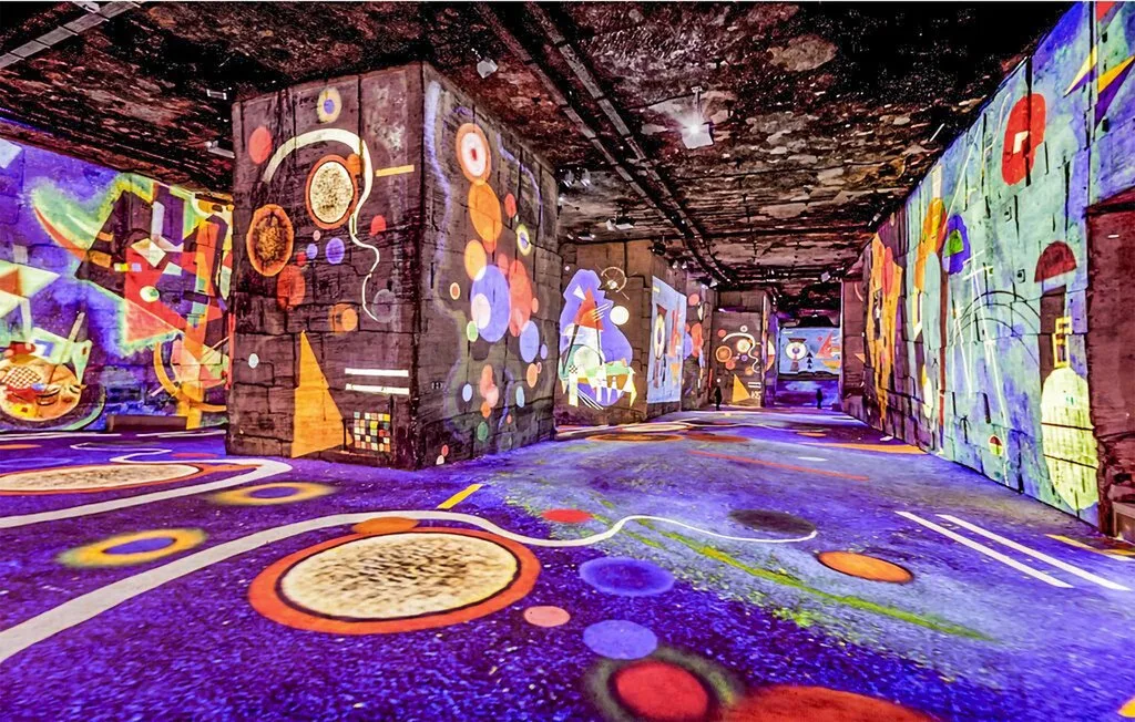 Una colorida instalación de arte interior cubre las paredes y el suelo con patrones proyectados.