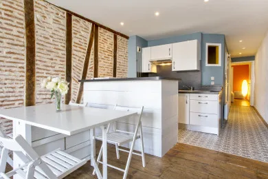 A bright kitchen with a white counter and a dining table in the foreground.
