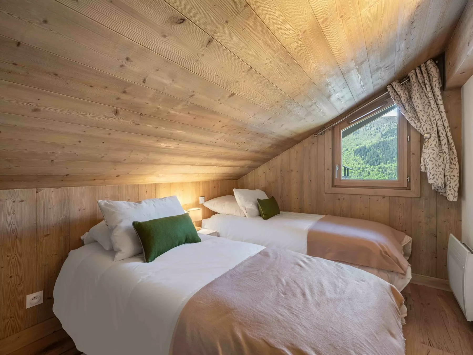 Un dormitorio con dos camas bajo un techo inclinado de madera y una ventana.