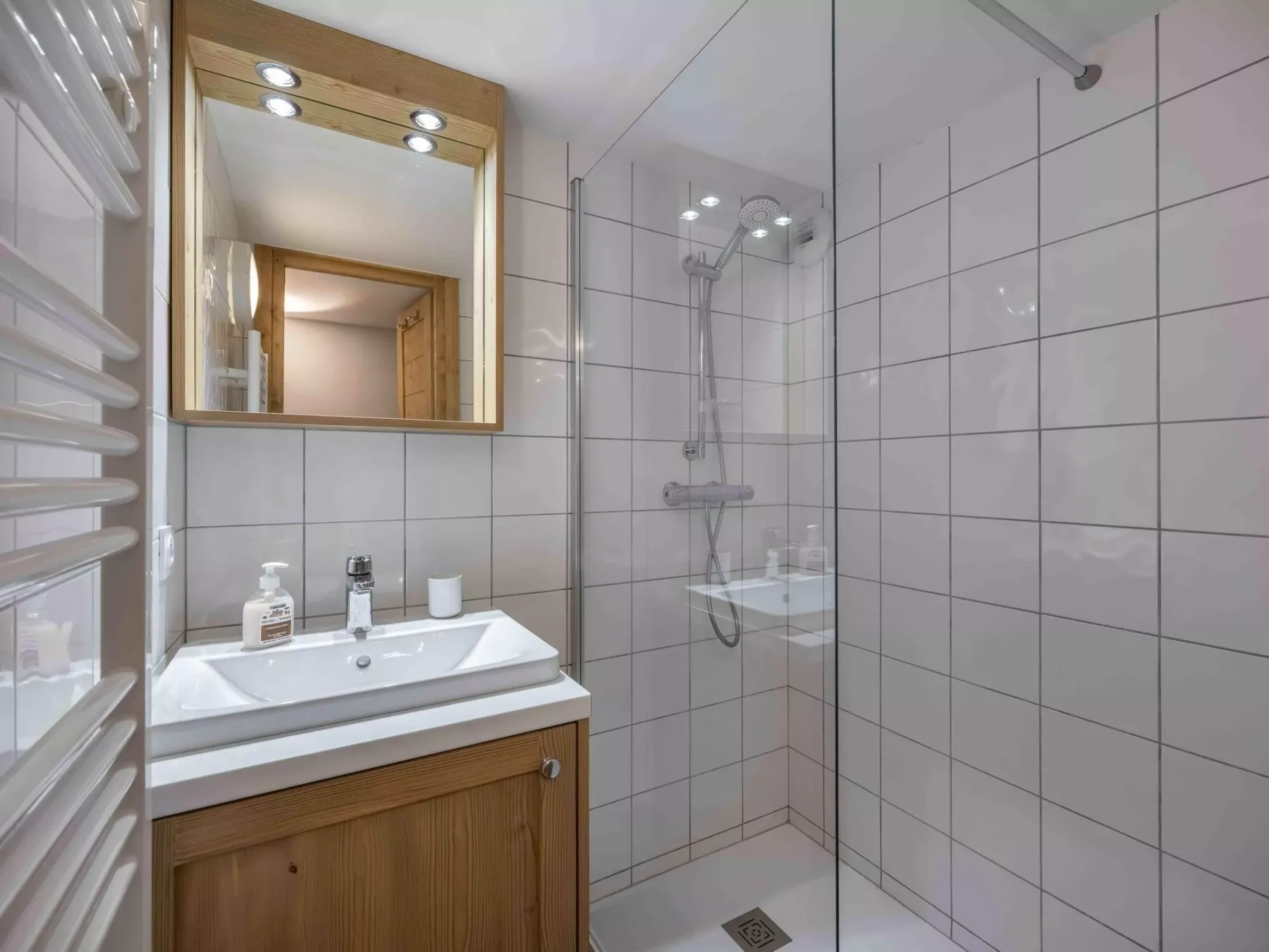 Un baño con azulejos, lavabo, espejo y ducha de vidrio.