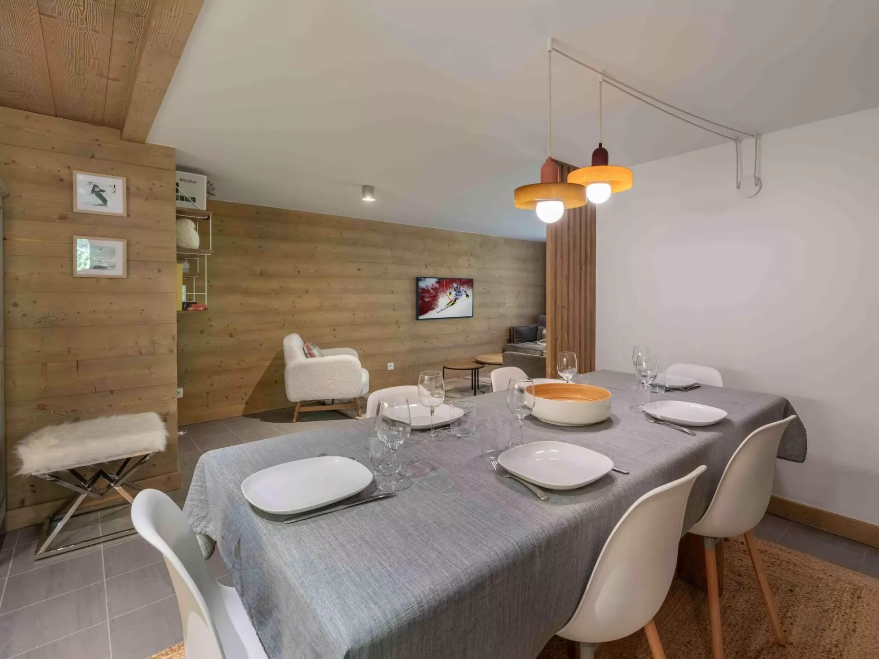 Comedor con una mesa puesta y paneles de madera en la pared.