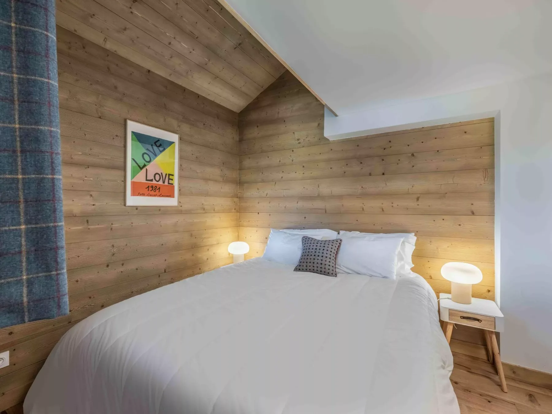 Un dormitorio con una cama tendida y paredes revestidas de madera.