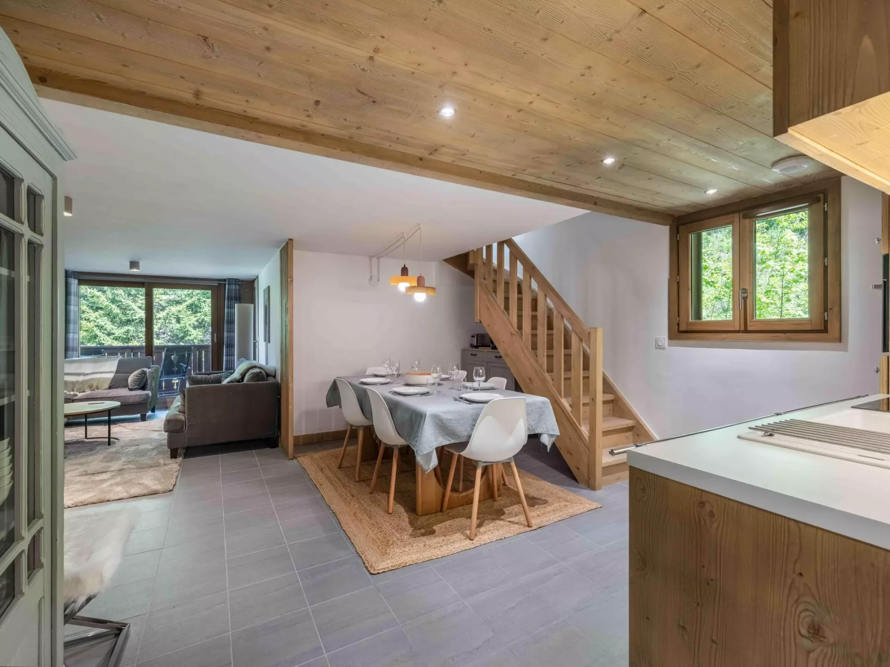 An open dining area with a table beside a wooden staircase.