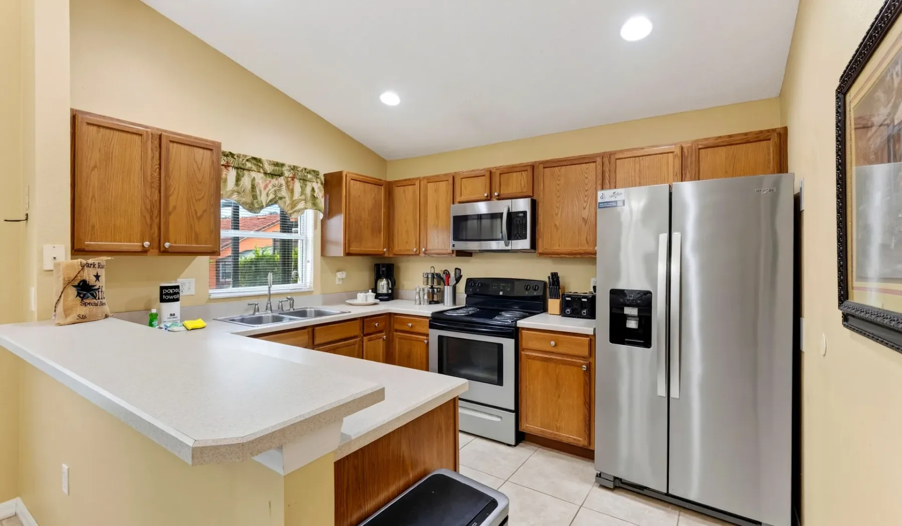 Una cocina luminosa con gabinetes de madera, una isla central y electrodomésticos de acero inoxidable.