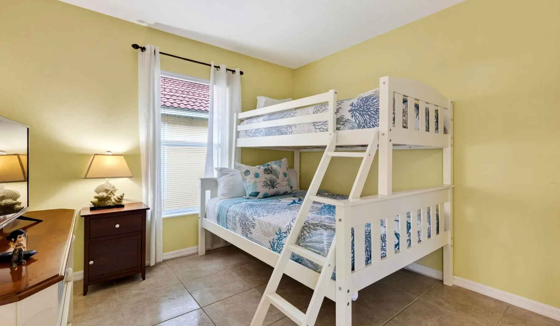 Un dormitorio con una litera blanca y una ventana sobre un suelo de baldosas.