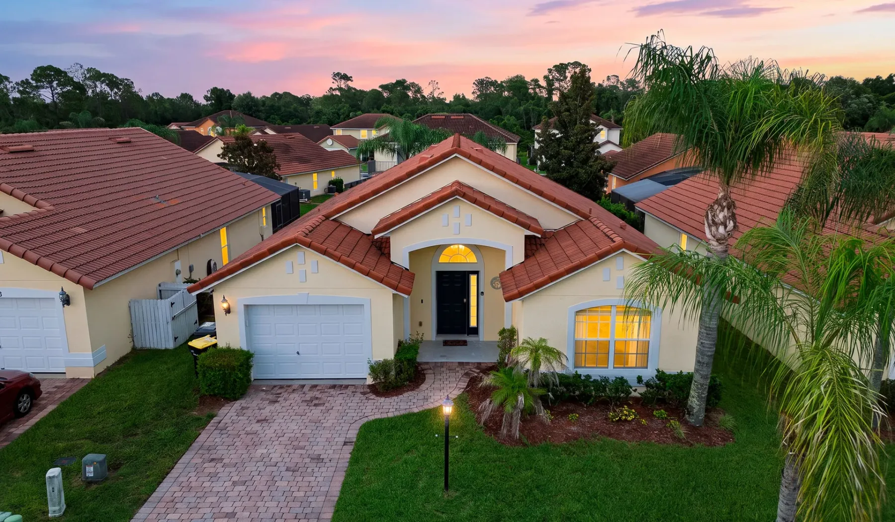Una casa suburbana con techo de tejas y entrada para vehículos al atardecer.