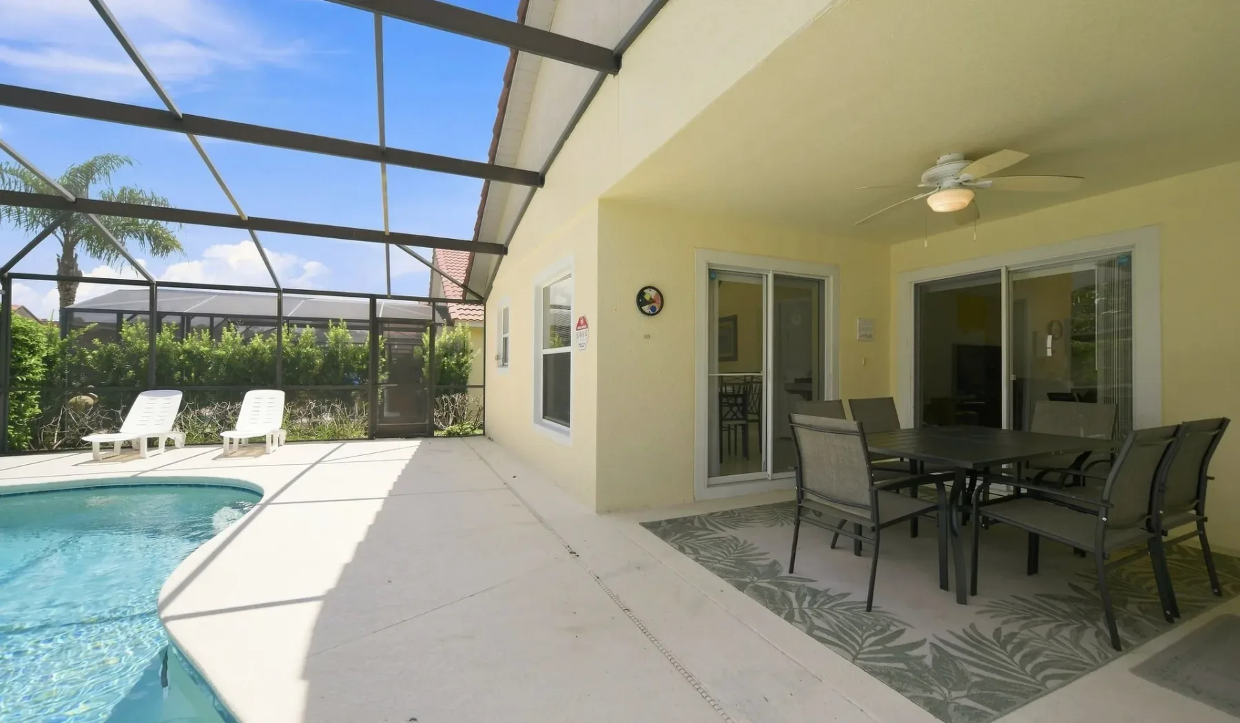 Un patio con piscina y comedor al aire libre, rodeado por una pantalla.