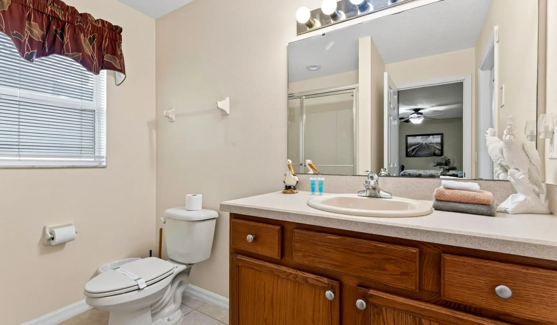 Un tocador de baño con lavabo e inodoro junto a una ventana.