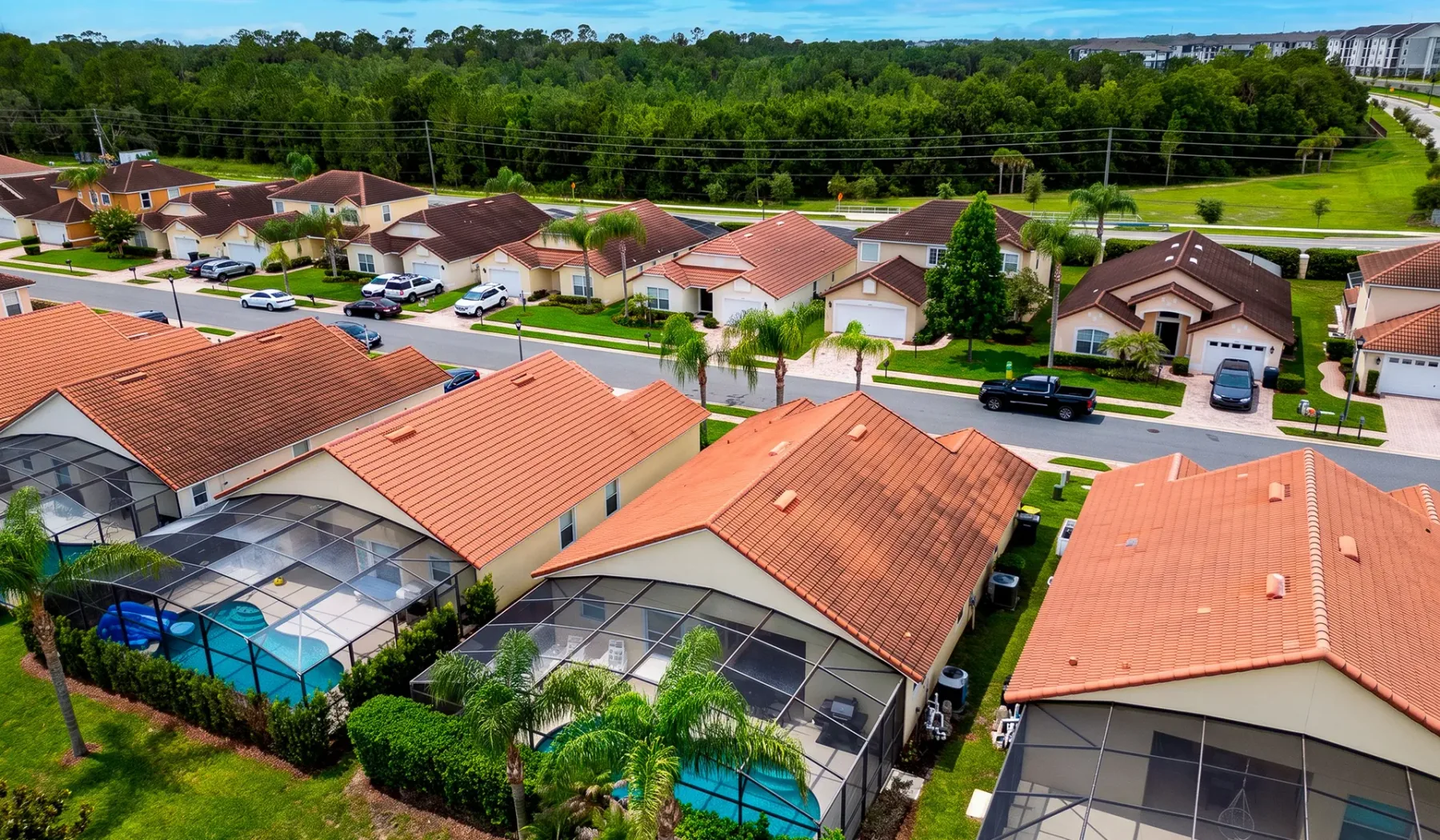 Vista aérea de un vecindario residencial con casas de techo rojo y piscinas.