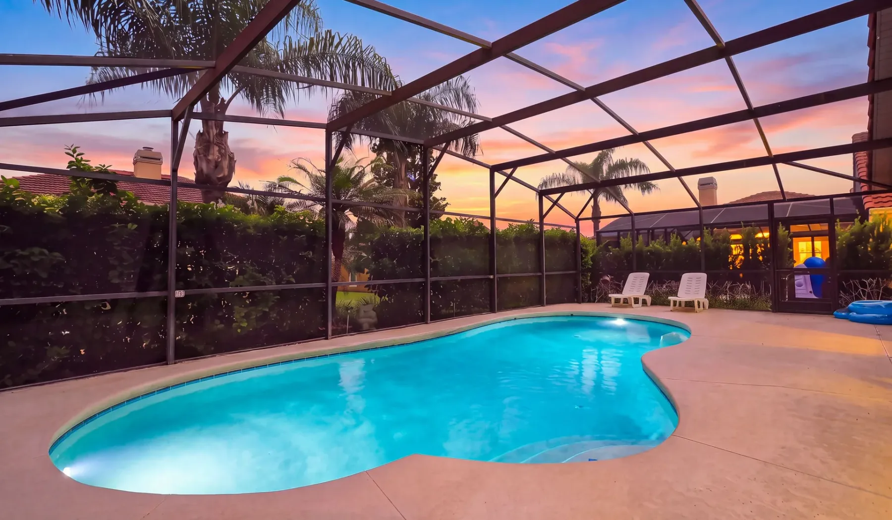 Una piscina está bajo un cerramiento con malla al atardecer.