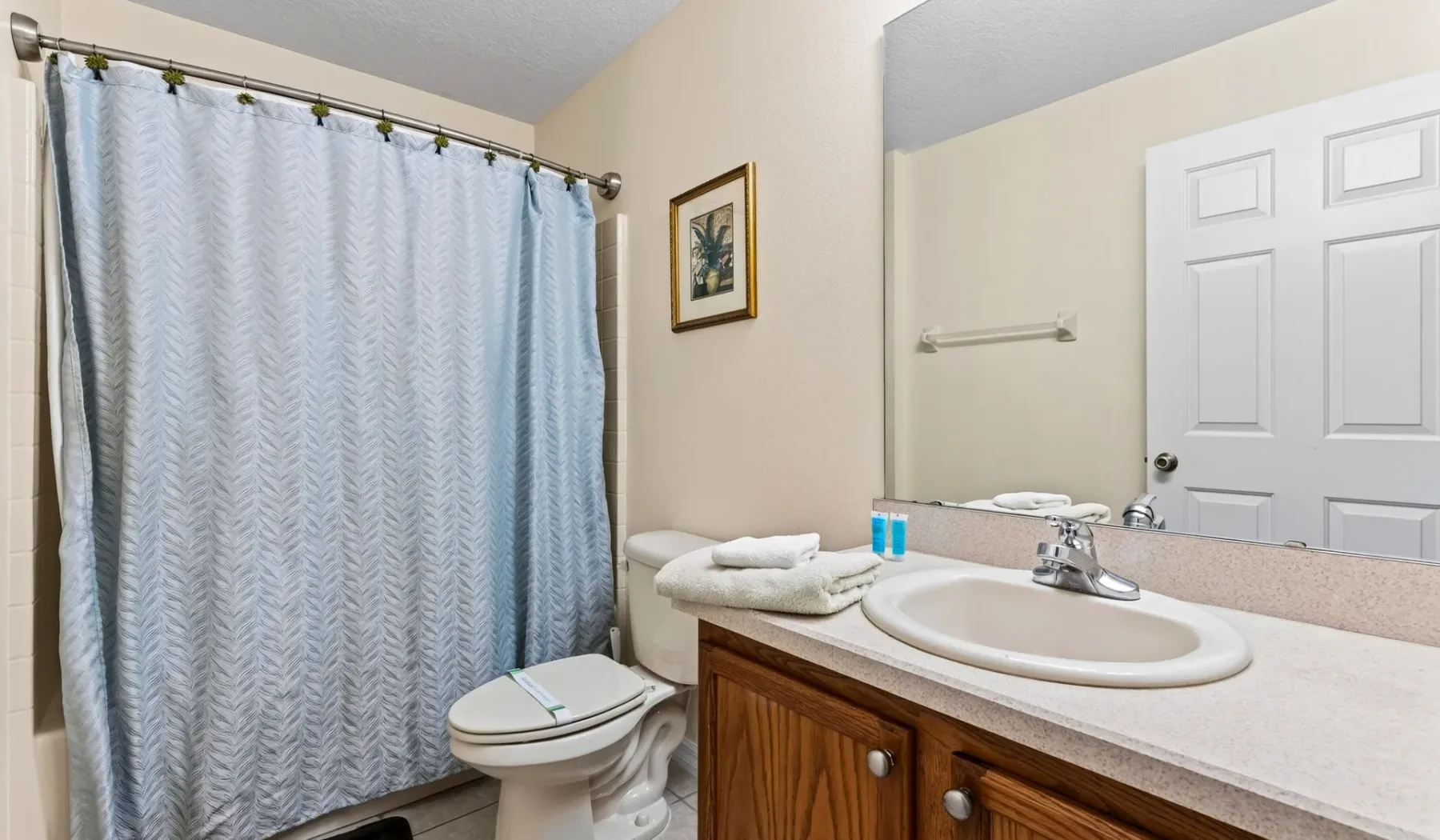 Baño con lavabo, inodoro y cortina de ducha.