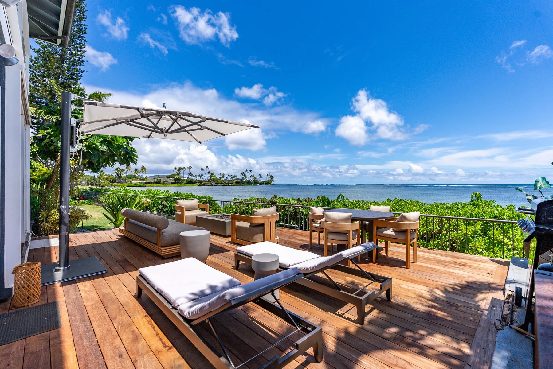 A sunny outdoor deck with lounge seating and a view of the water.