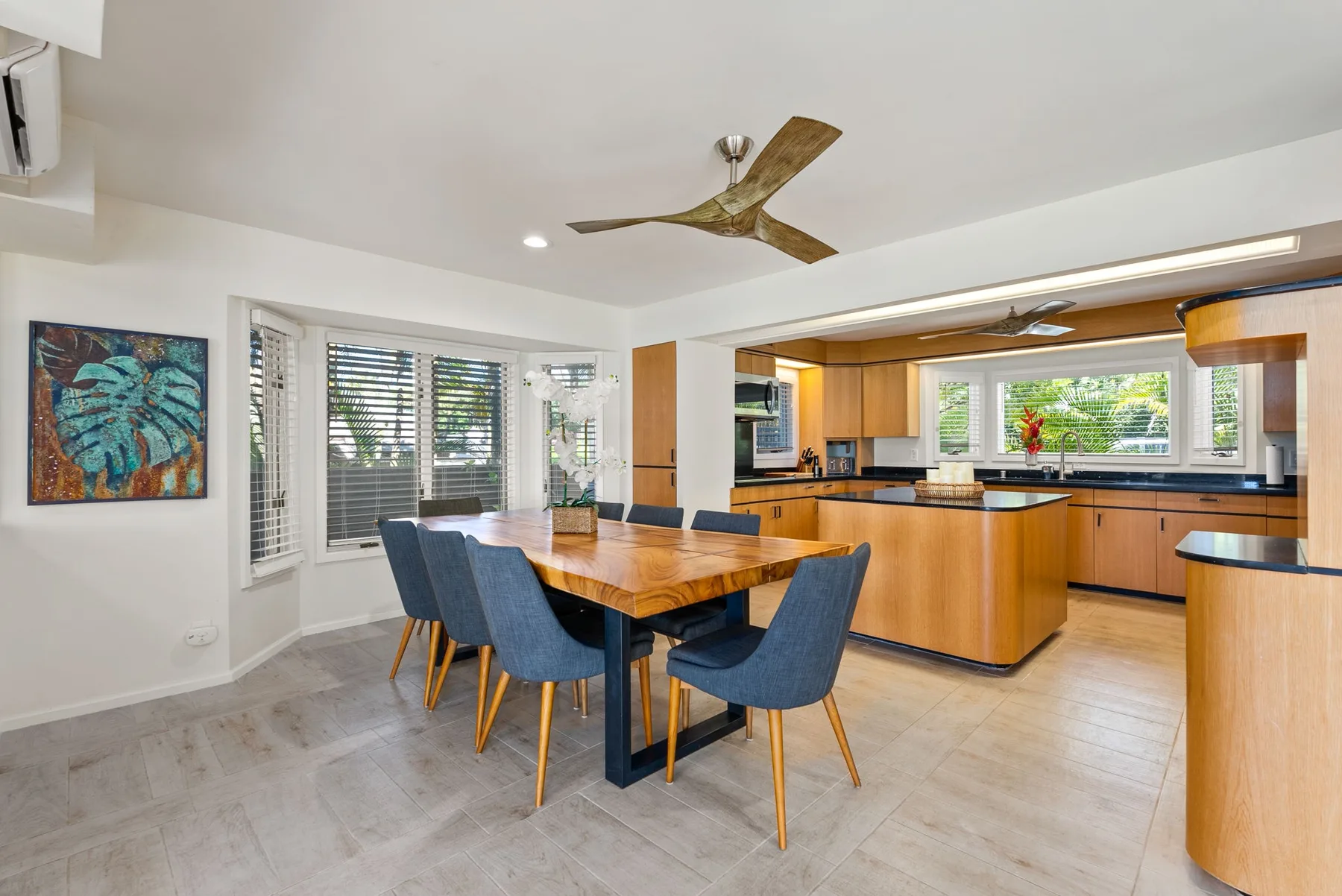A dining area opens into a kitchen, with a wooden table and blue seating.