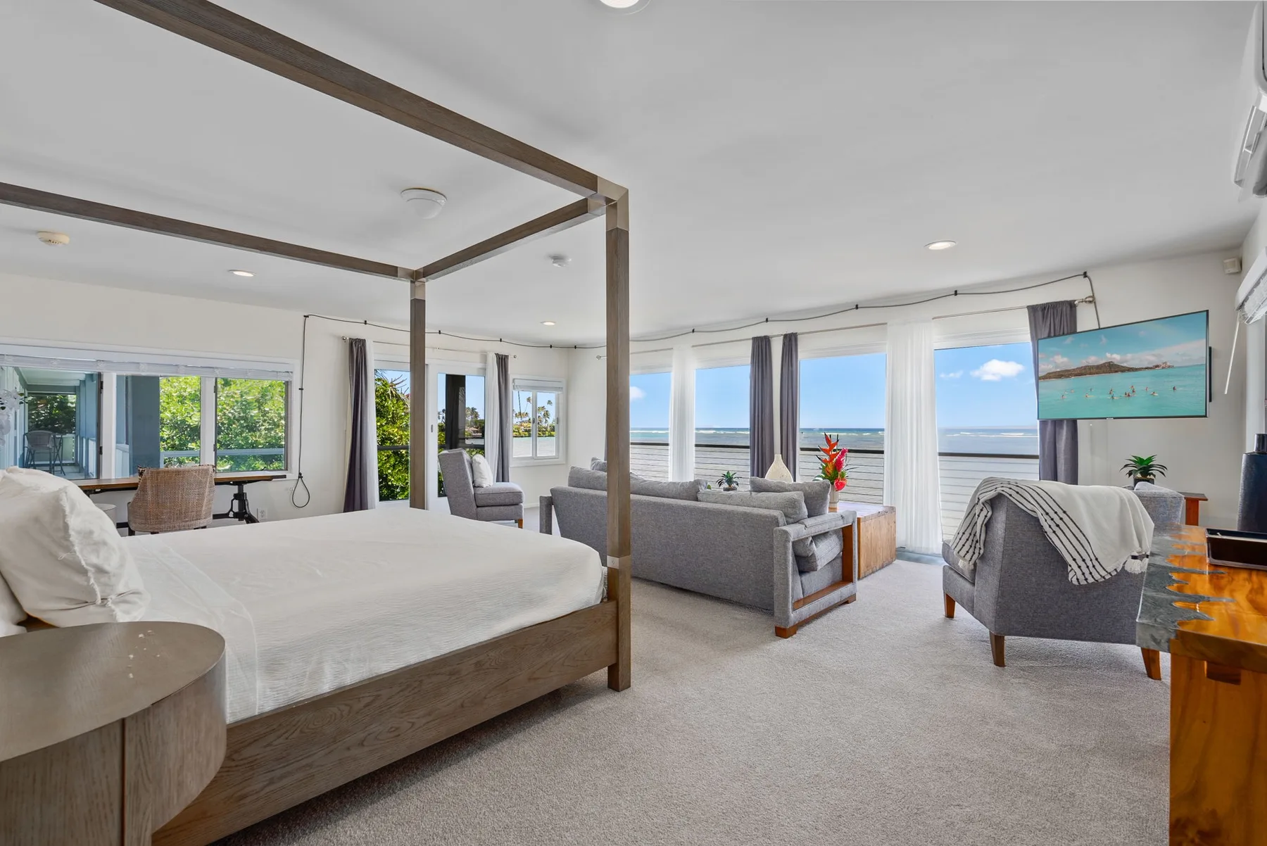 A bright bedroom and sitting area with large windows overlooking the water.