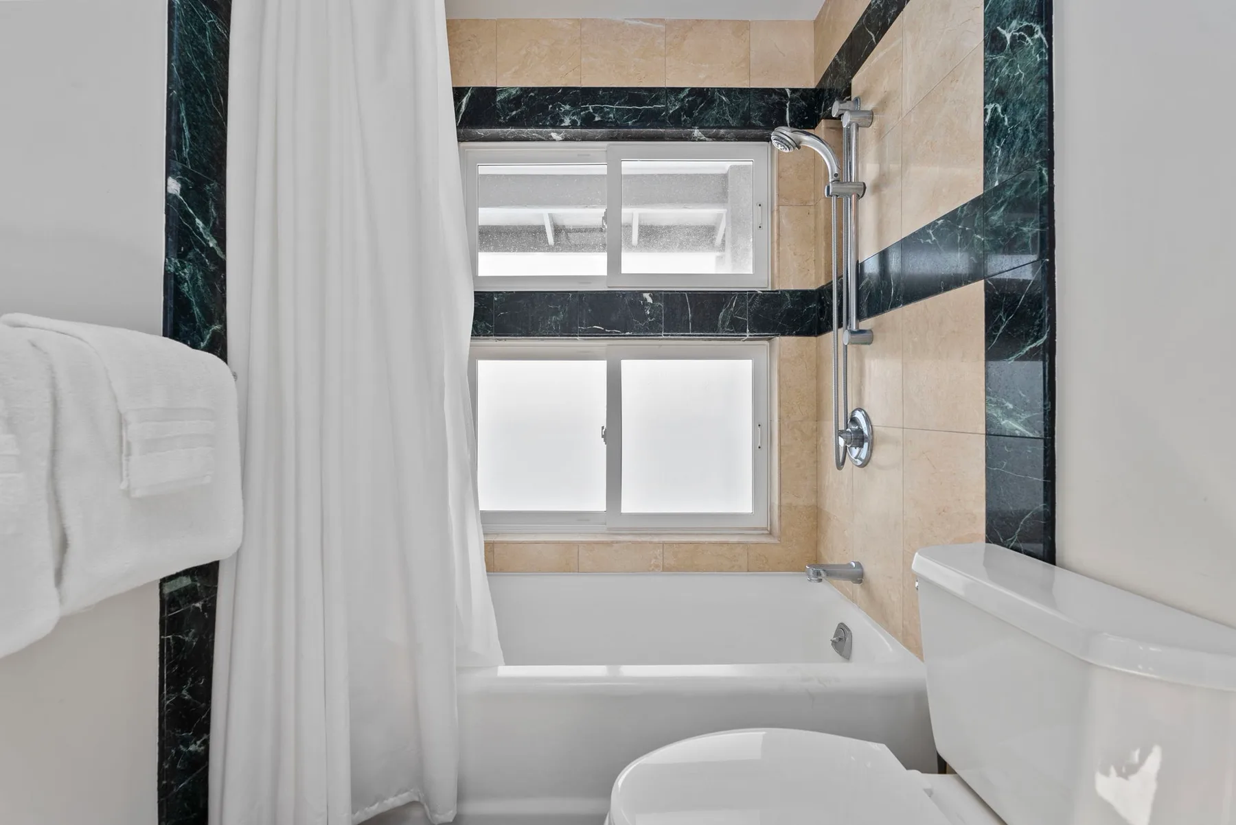 A bathroom with a bathtub, shower, and frosted windows.