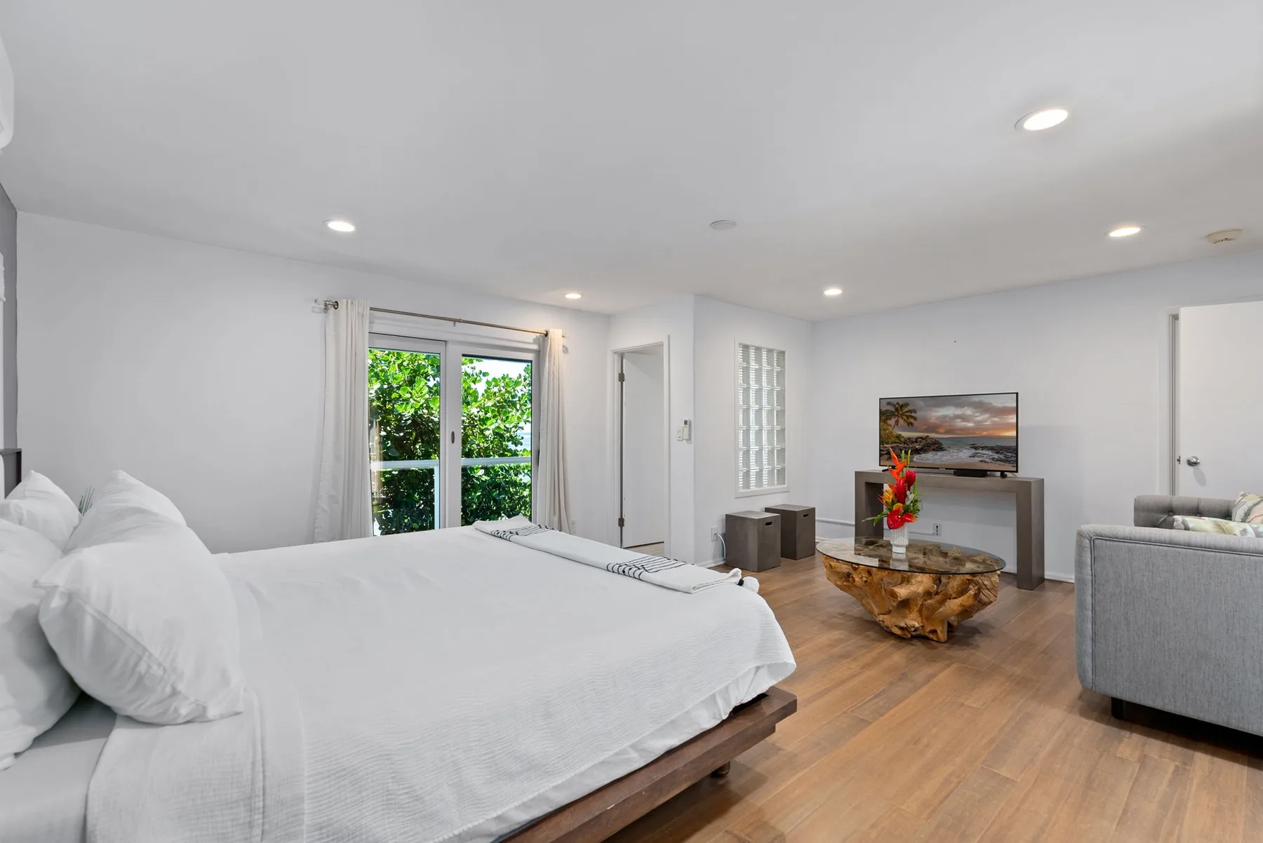 A bright bedroom with a large bed, a coffee table, and a seating area.