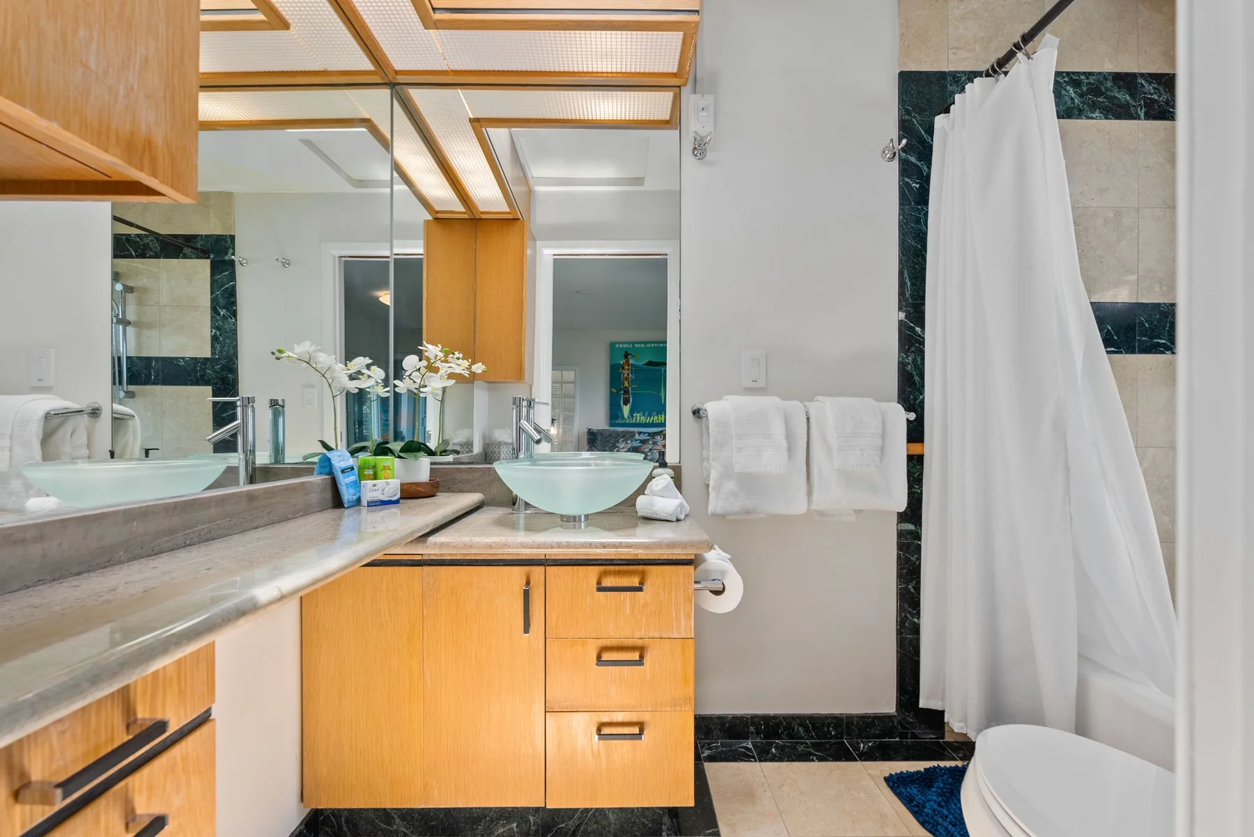 A bathroom vanity with a sink and mirror beside a curtained shower.