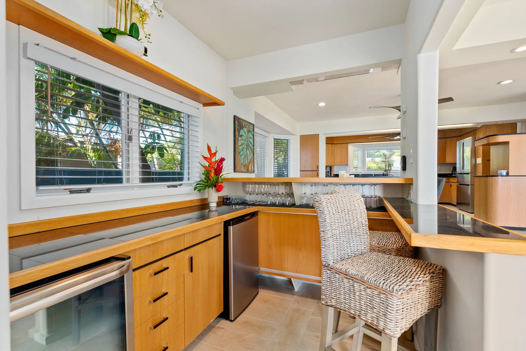 A bright kitchen with a counter, bar seating, and large windows.