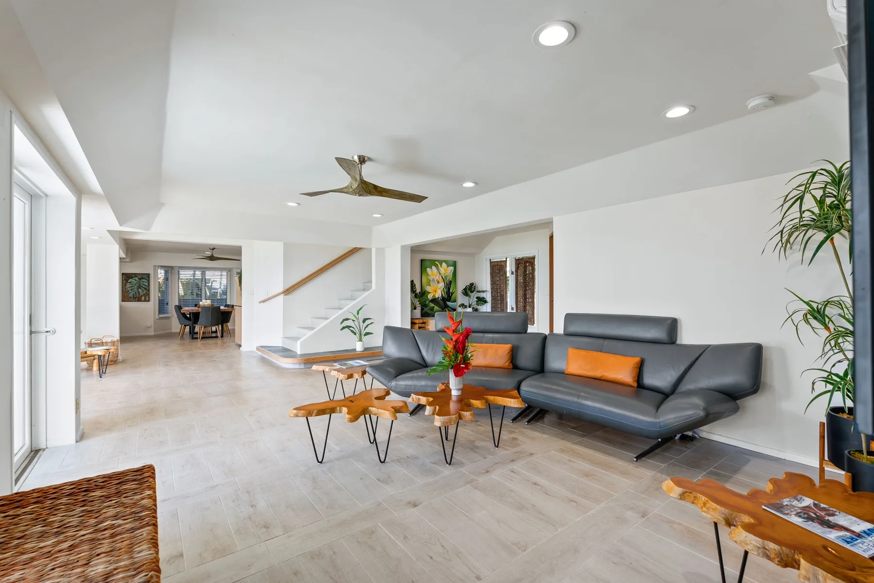 A bright living room with dark seating and low wooden coffee tables.
