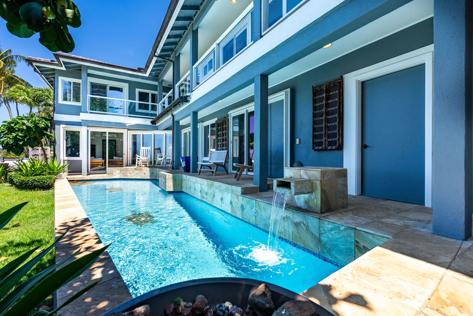 A swimming pool runs alongside a modern multi-story house.