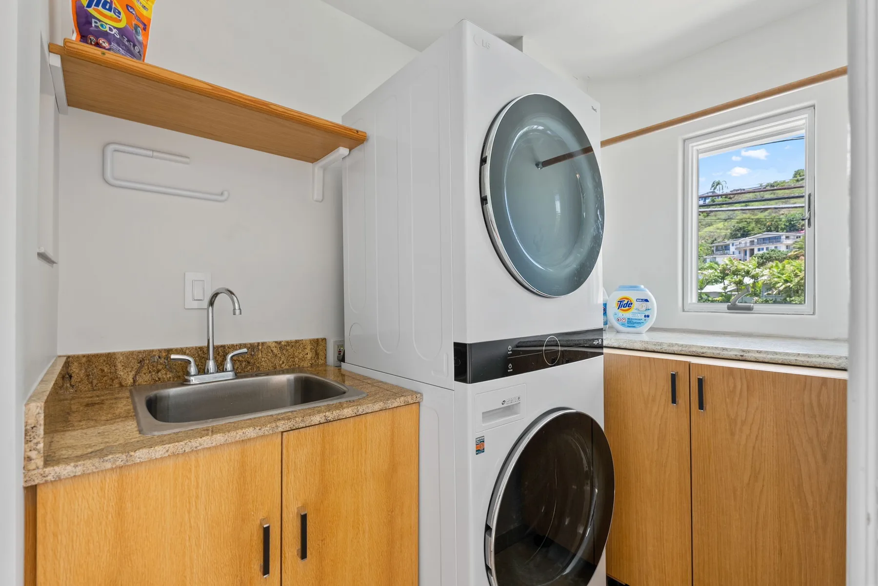 A laundry area with a stacked washer and dryer beside a sink and countertop.