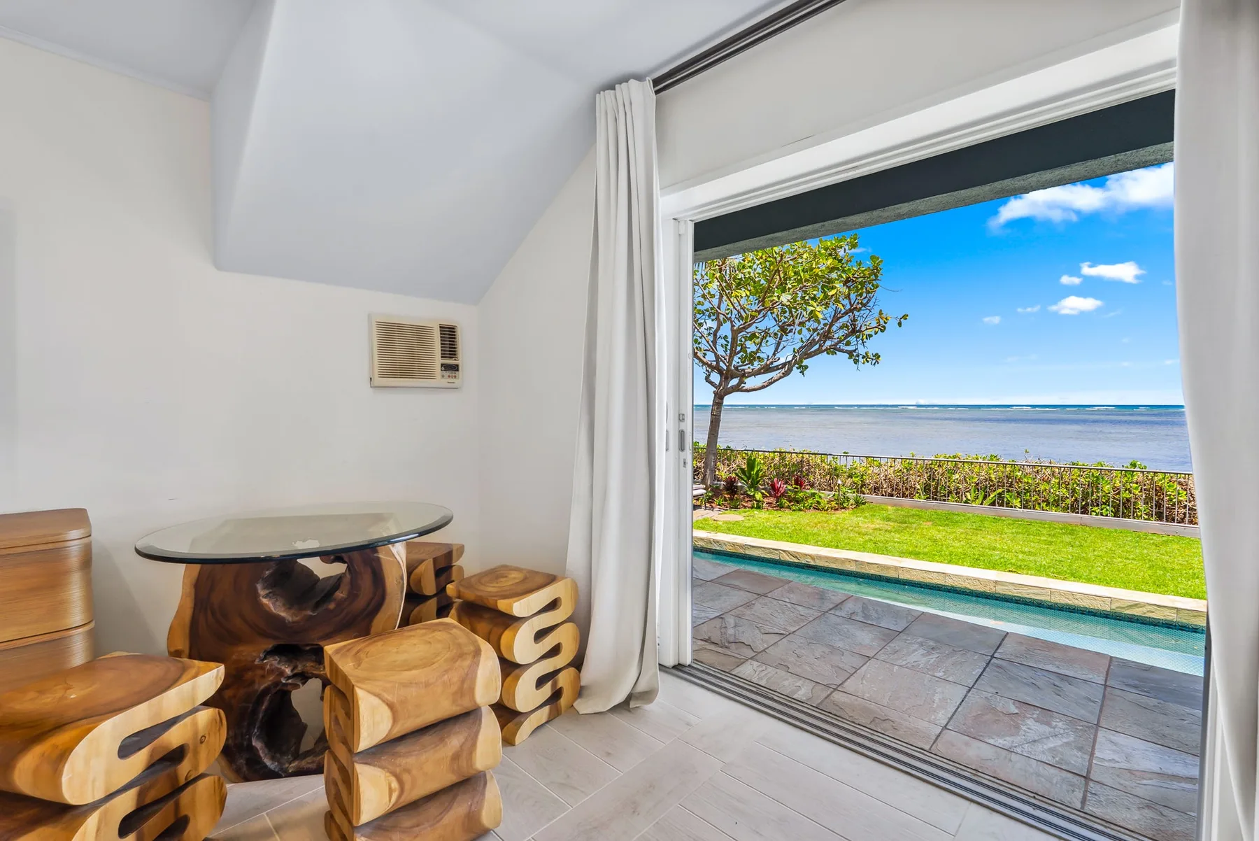 A dining area opens onto a patio overlooking the ocean.