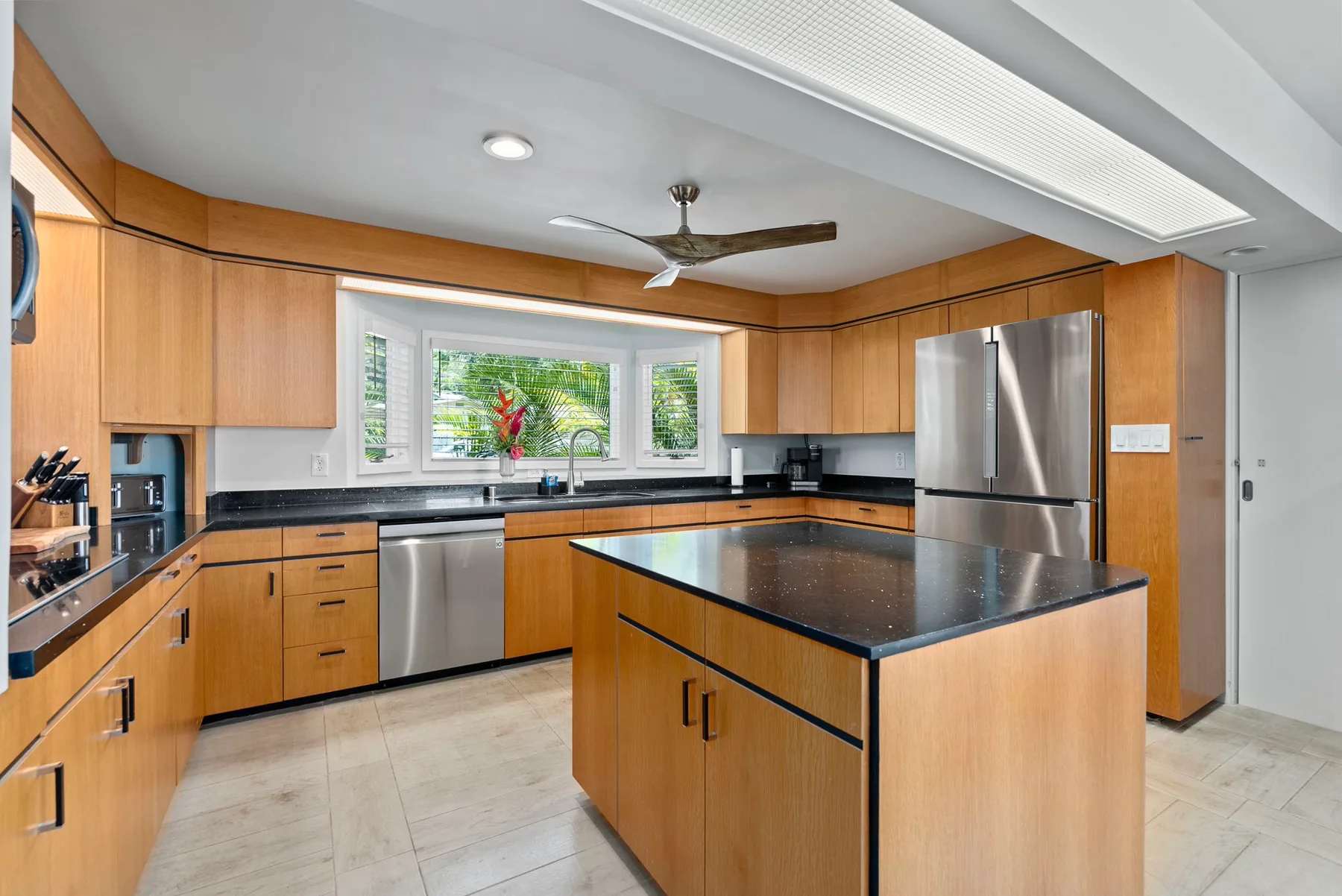 A spacious kitchen with wood cabinets, dark countertops, and a central island.