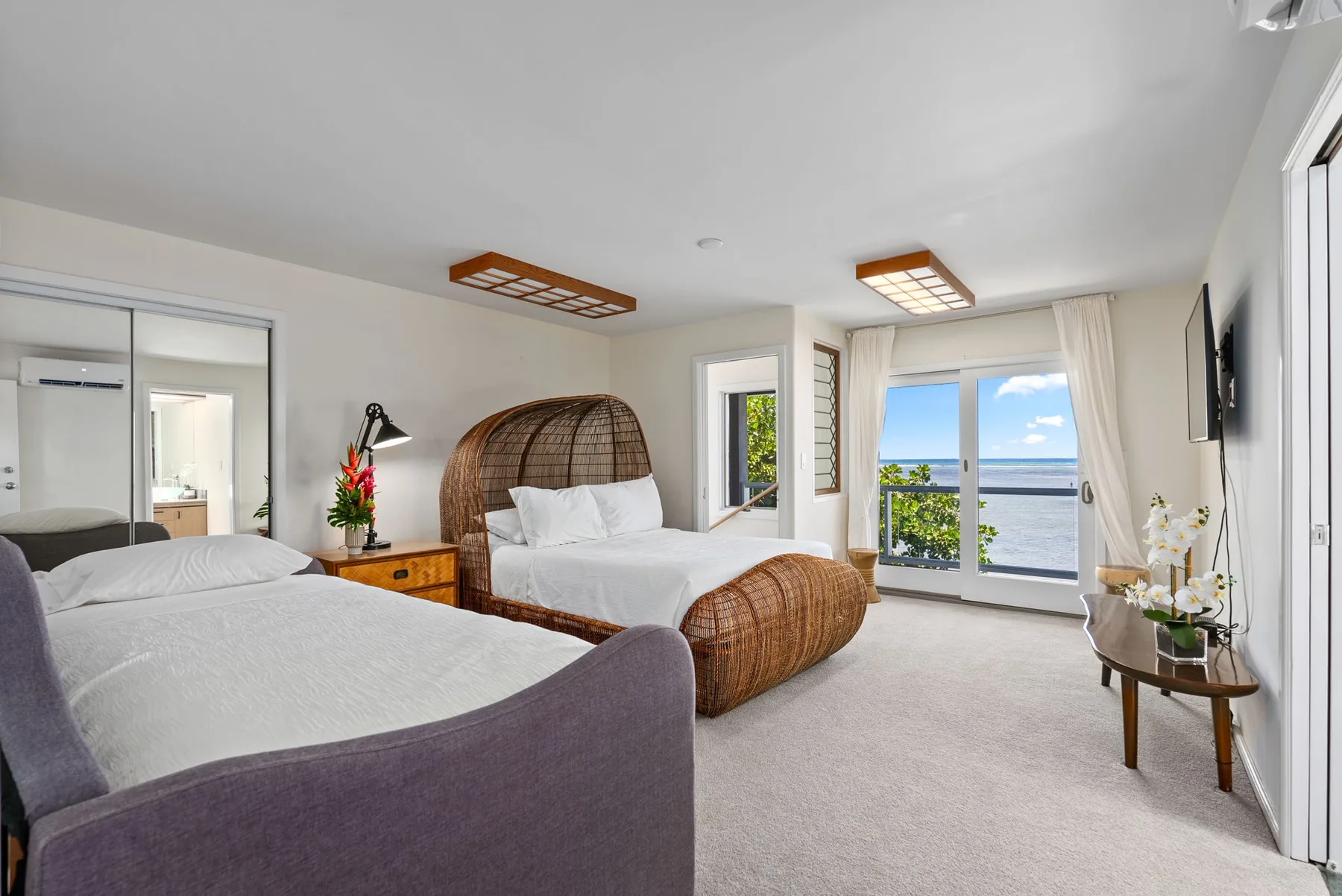 A bright bedroom with two beds and a window overlooking the water.