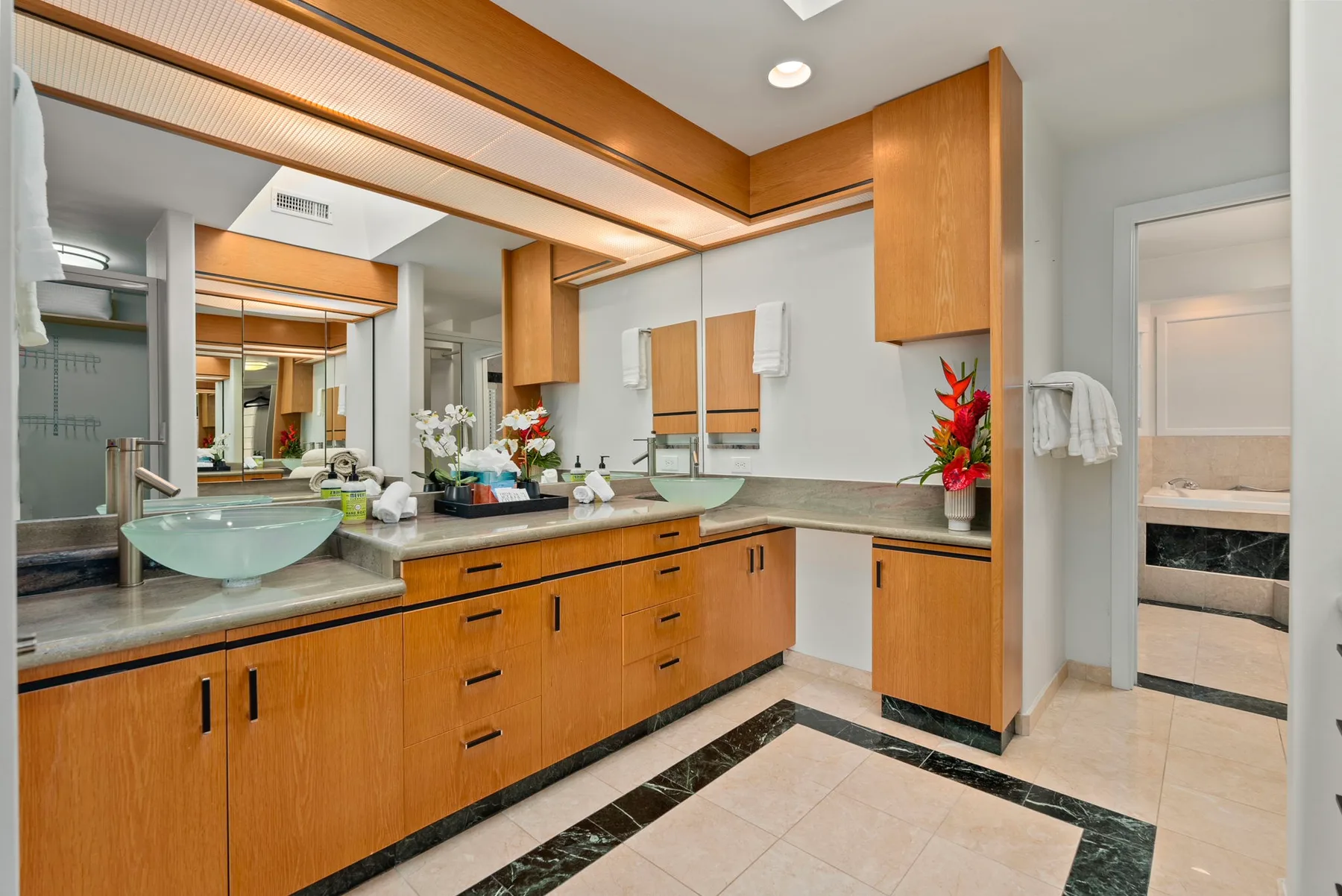 A bathroom vanity with wooden cabinets, mirrors, and a countertop.