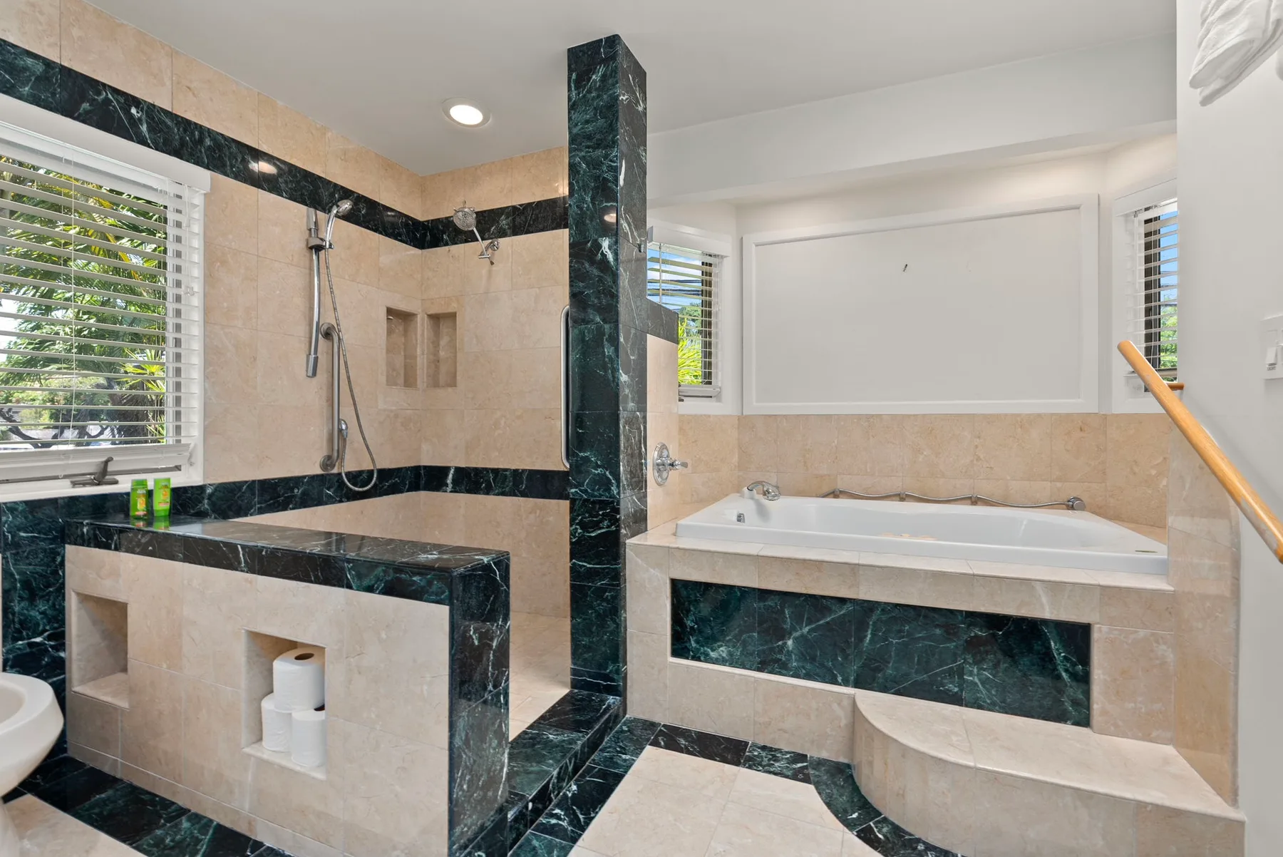 A tiled bathroom with a glassless shower area and a bathtub.