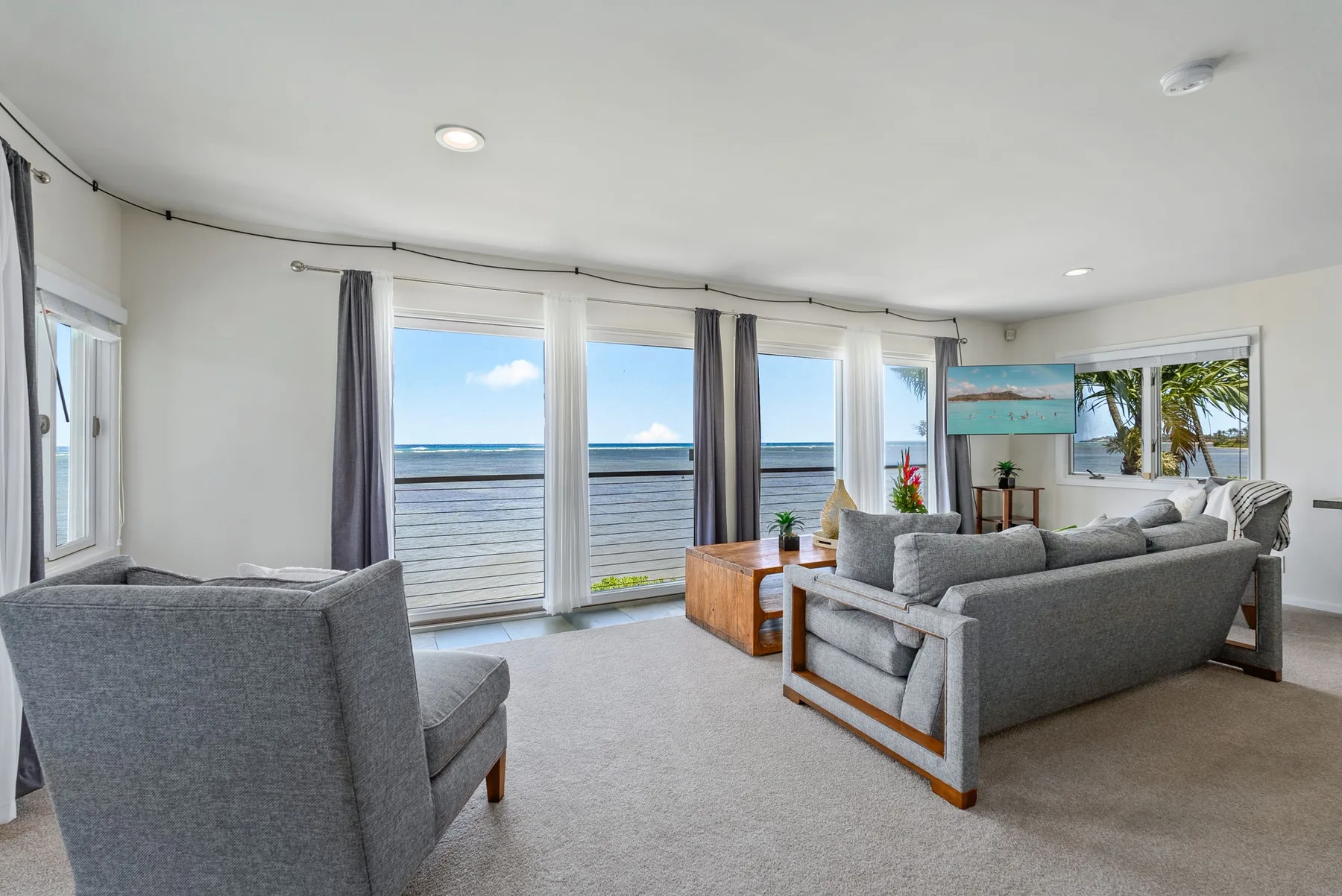 Living room with seating beside large windows overlooking the ocean.