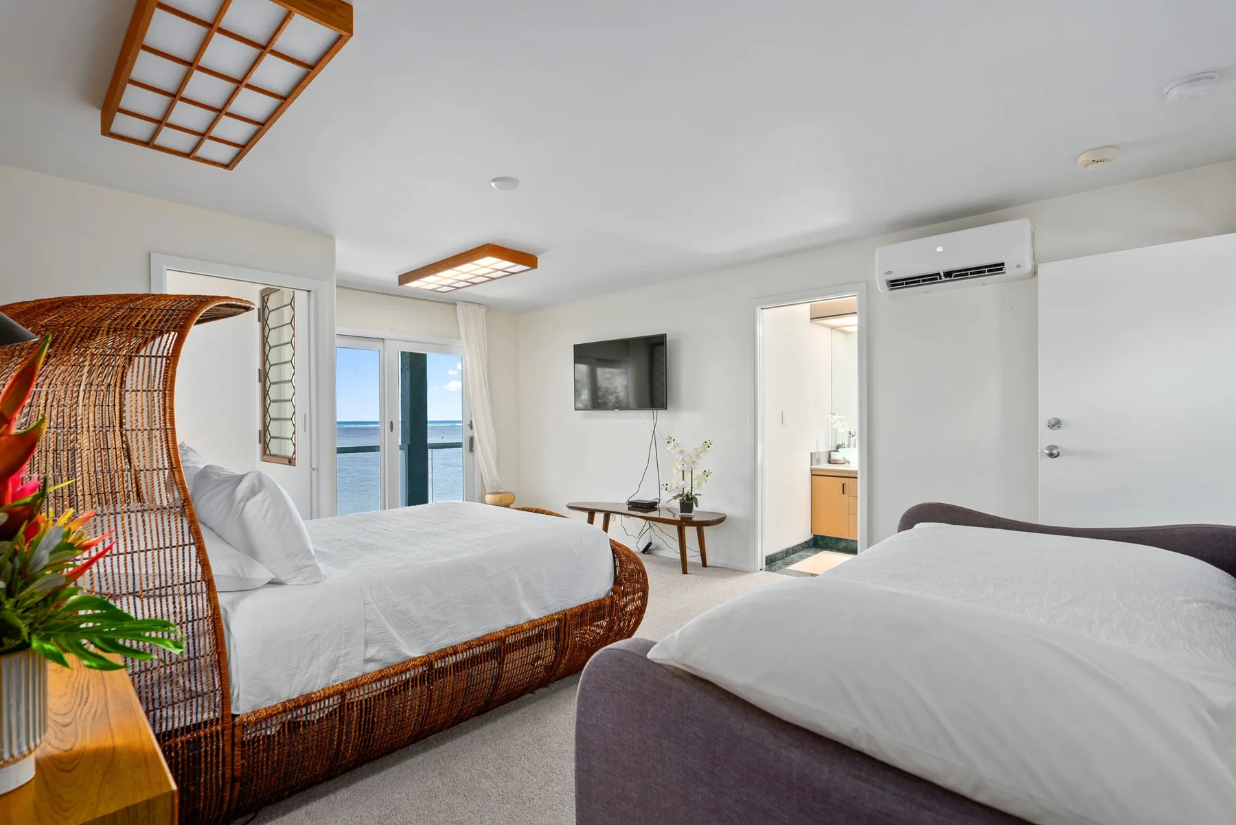A bedroom with two beds and glass doors opening onto a balcony.