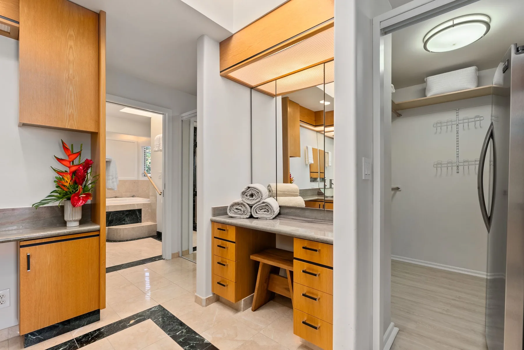 A bathroom vanity with mirrors and wooden cabinetry stands beside an open closet.