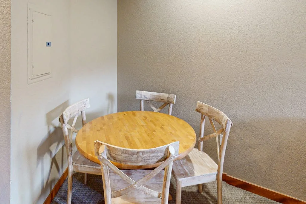 A round wooden table with chairs sits in a small dining area.