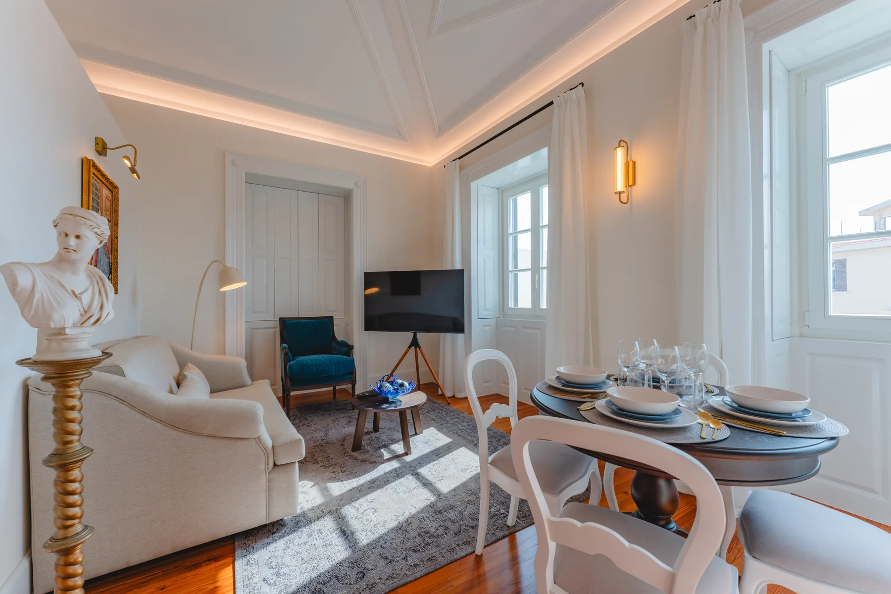 Una luminosa sala de estar y comedor con asientos, un televisor y una mesa puesta.