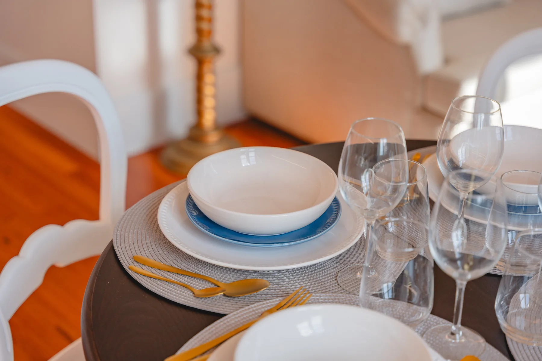 Una mesa de comedor está puesta con platos, copas y cubiertos.