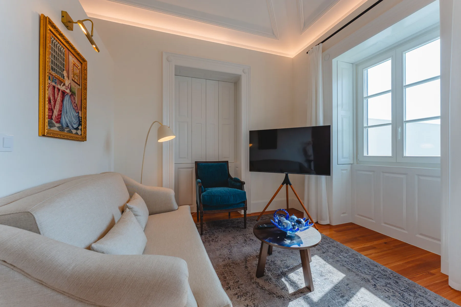 Una sala de estar con un sofá, un televisor y ventanas grandes.